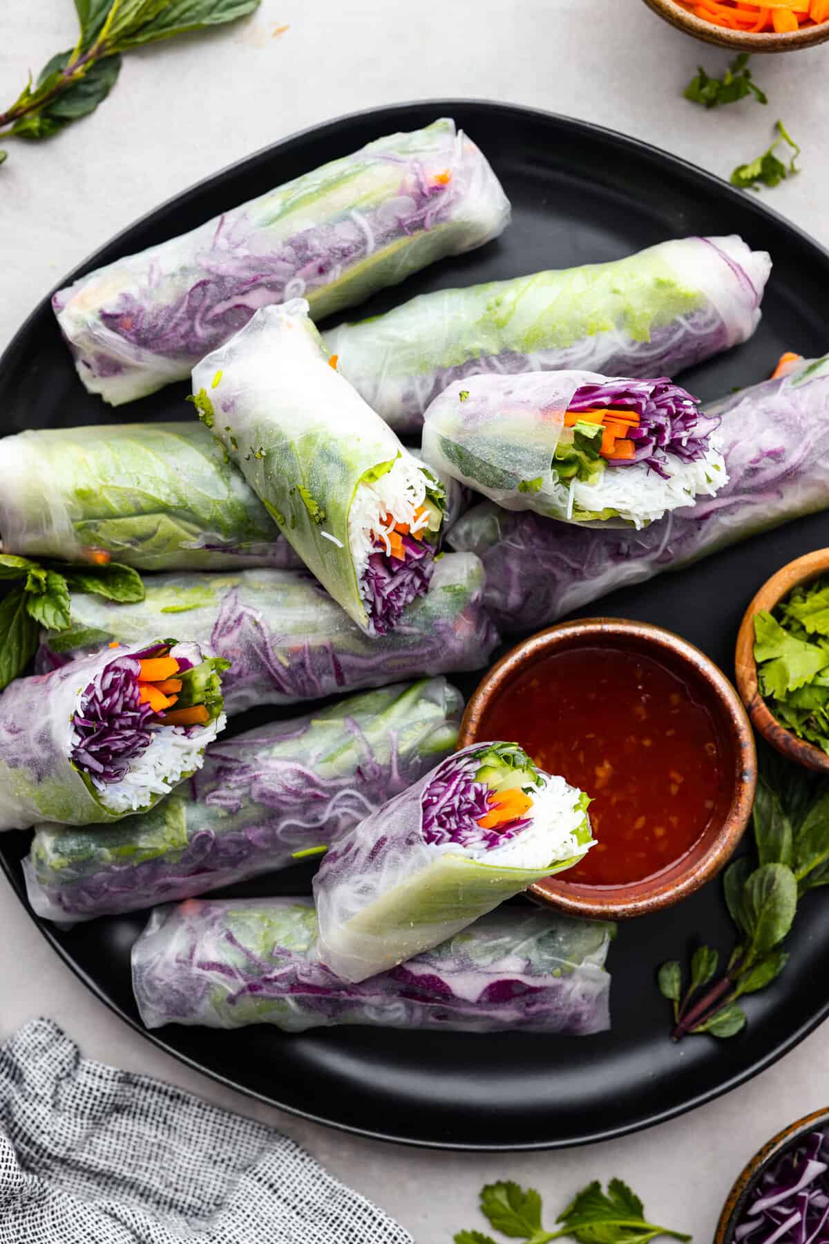 Spring rolls on a plate with chili dipping sauce.